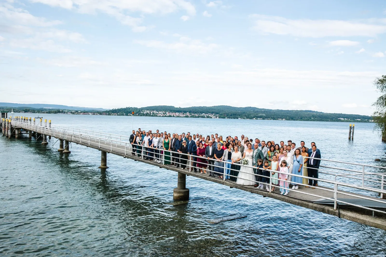 Hochzeitsgesellschaft auf einem langen Steg im Bodensee