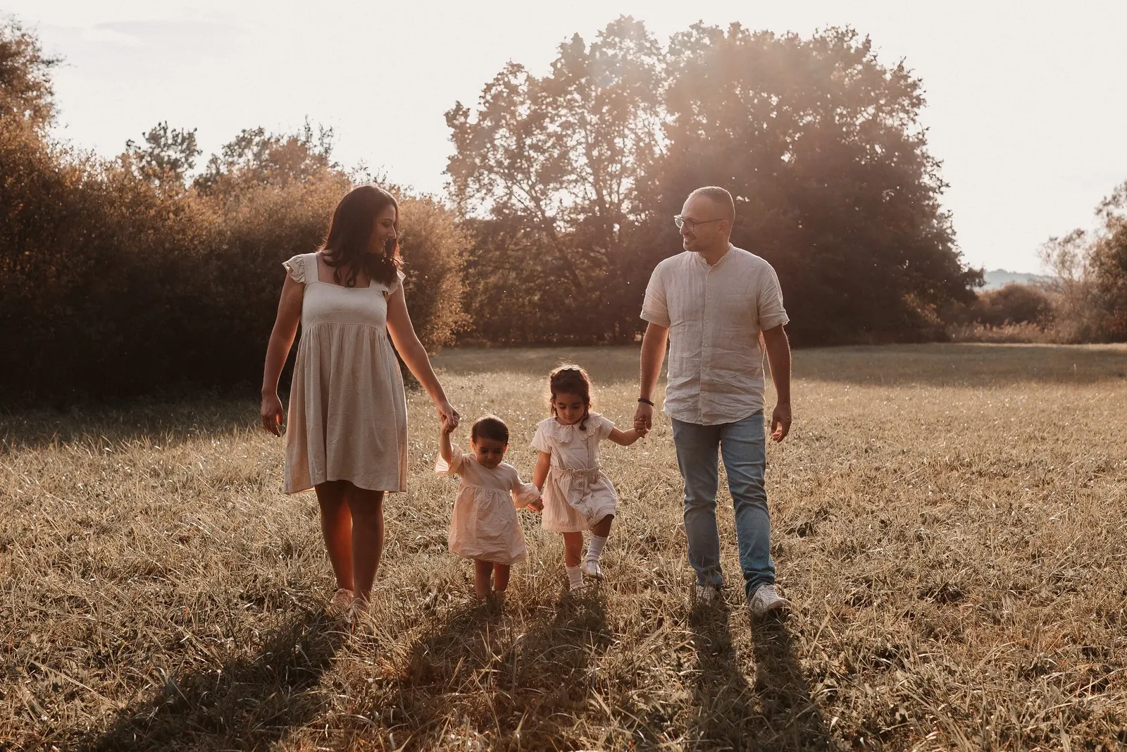 Familie spaziert im Abendlicht über eine Wiese